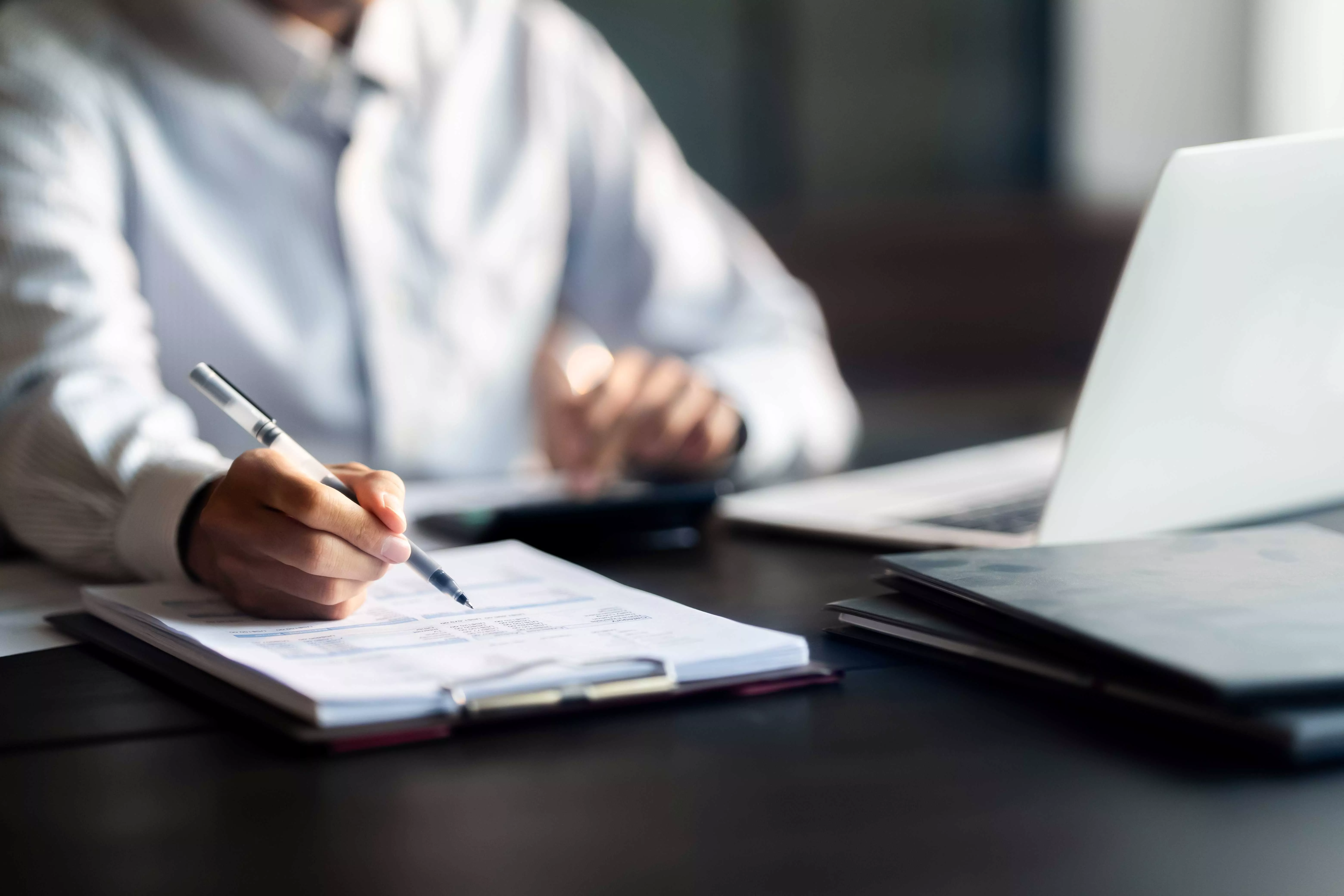 Person in einem Gespräch vor einem Laptop macht sich Notizen, symbolisiert persönliche Steuerberatung und individuelle Betreuung